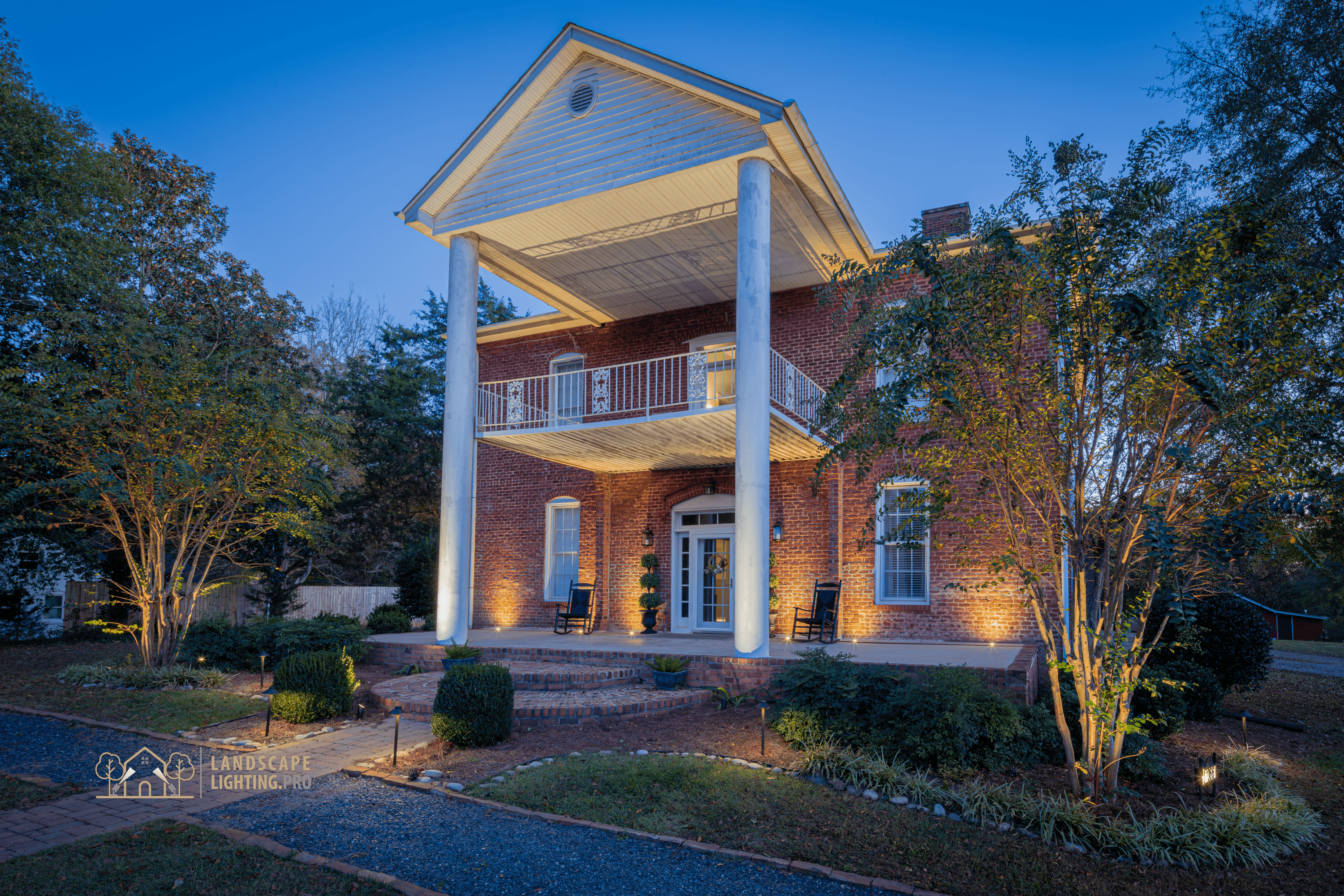 An 1850 historic brick home illuminated at dusk with embedded landscape lighting