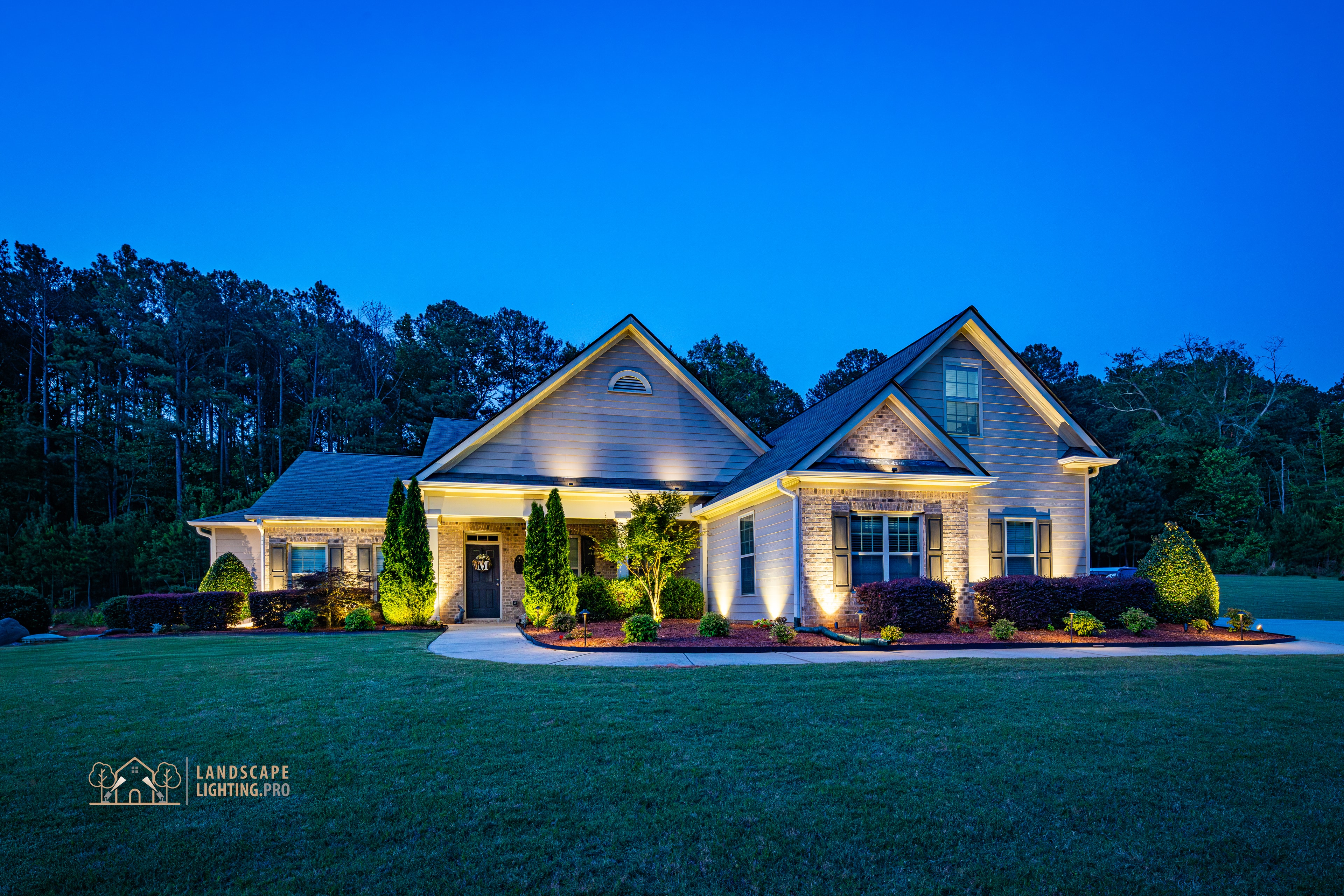 Home illuminated with architectural and landscape lighting at dusk